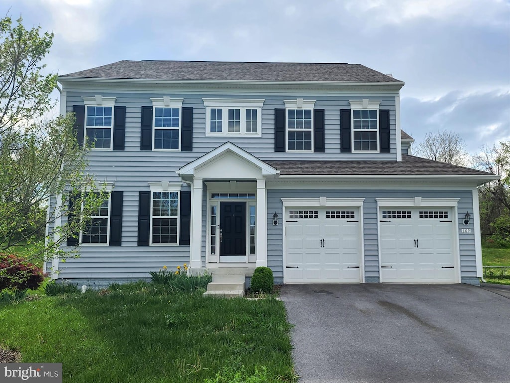 view of front of property with roof with shingles, aphalt driveway, and an attached garage