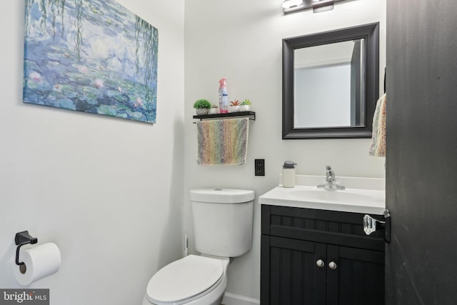 bathroom featuring toilet, baseboards, and vanity