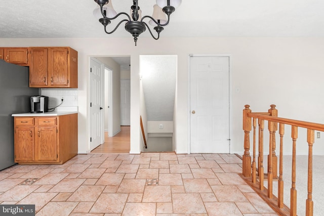 8005 Hillrise Ct, Elkridge, MD 21075 - kitchen with freestanding refrigerator, light stone finish floors, a chandelier, light countertops, and backsplash