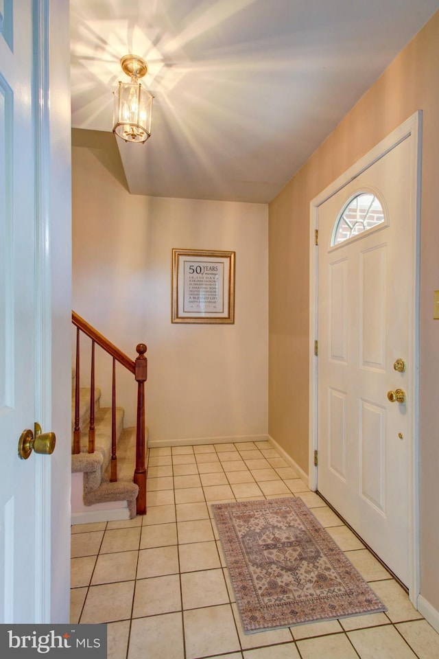 entryway featuring light tile patterned floors, stairway, and baseboards