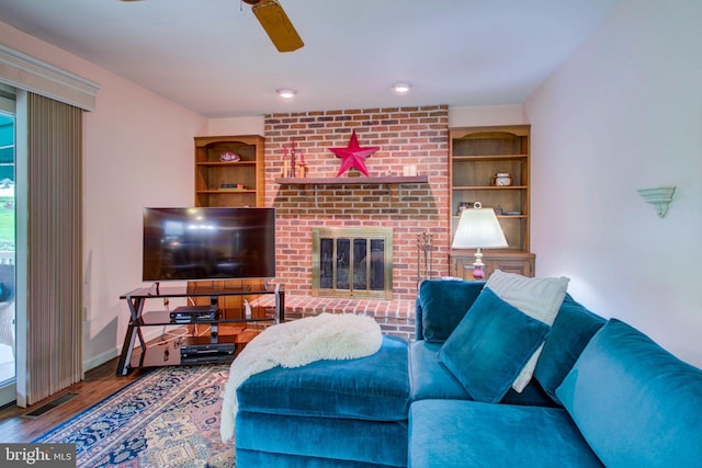 living room featuring ceiling fan, visible vents, baseboards, a fireplace, and wood finished floors