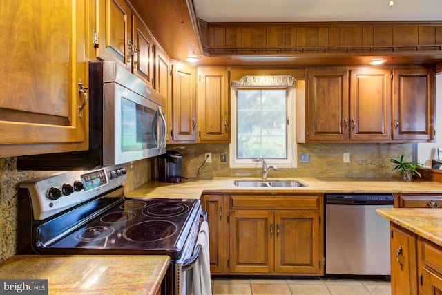 kitchen with brown cabinetry, stainless steel appliances, backsplash, and a sink
