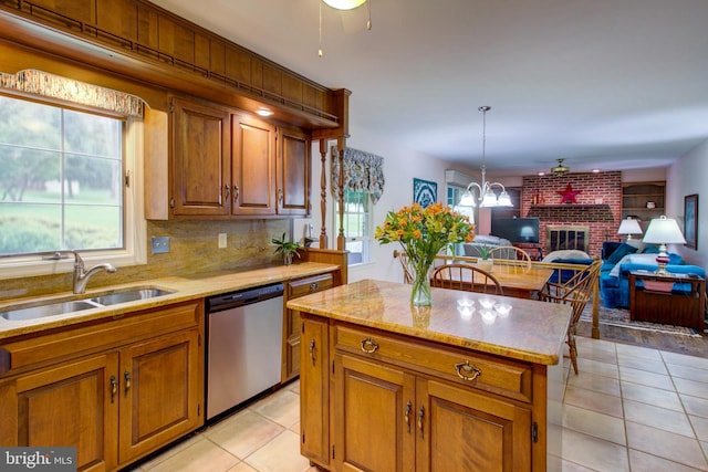 kitchen with light tile patterned floors, a sink, a kitchen island, open floor plan, and dishwasher