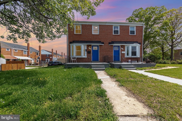 multi unit property with a front yard and brick siding