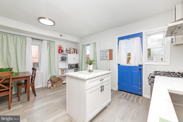 kitchen with light wood-type flooring, a healthy amount of sunlight, and white cabinets
