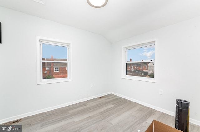 spare room featuring baseboards, visible vents, wood finished floors, and a wealth of natural light