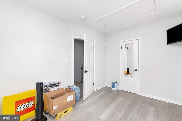 unfurnished room with attic access, wood finished floors, and baseboards