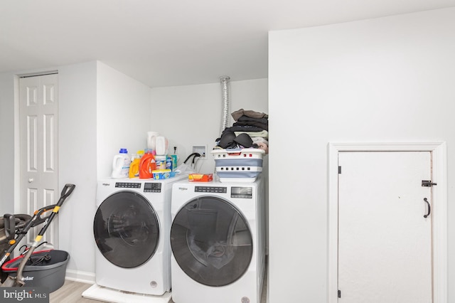laundry area with baseboards, light wood-style floors, separate washer and dryer, and laundry area