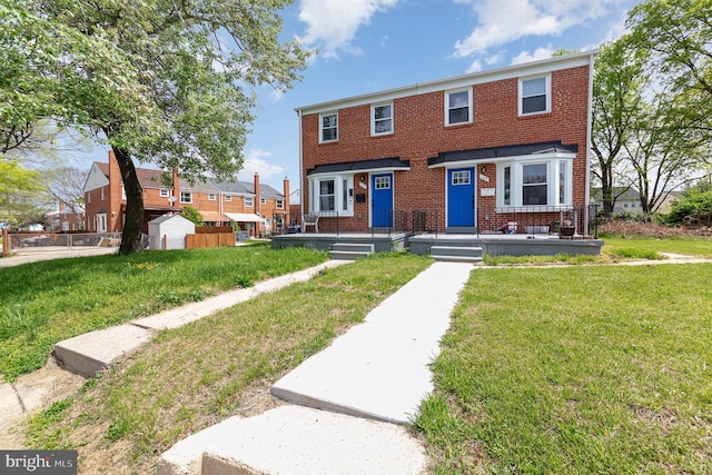 multi unit property featuring fence, a front yard, and brick siding