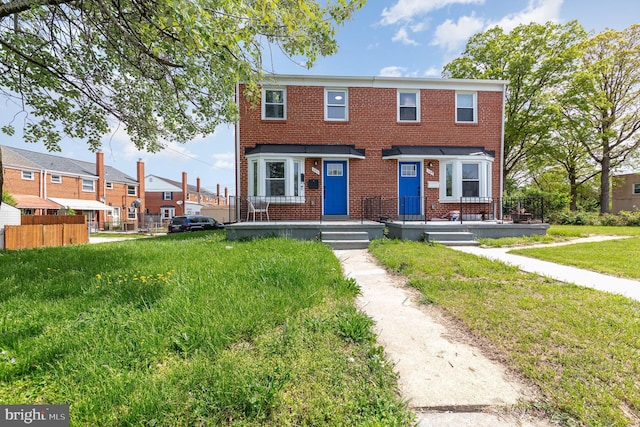 view of property featuring brick siding, fence, and a front yard
