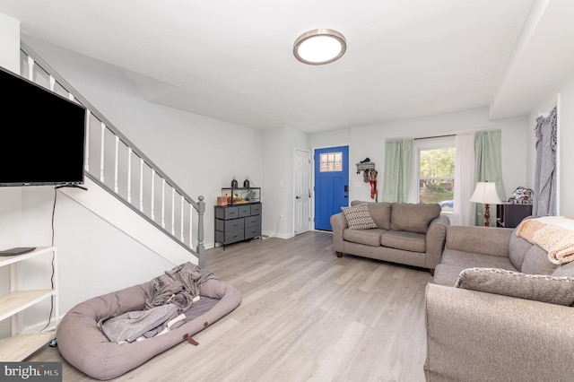 living area with stairs, wood finished floors, and baseboards