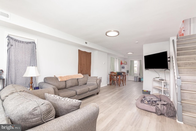 living area featuring wood finished floors, visible vents, and stairs