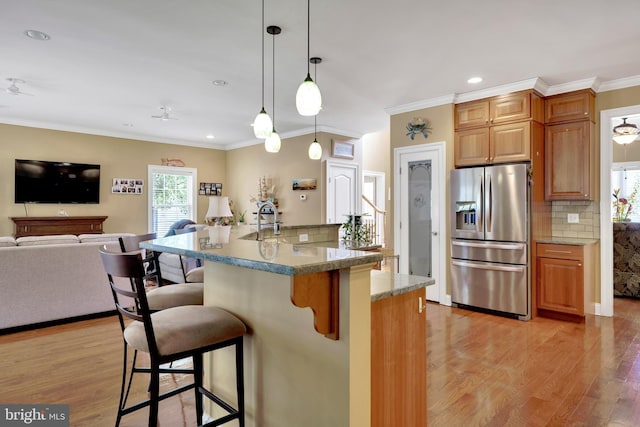 kitchen with a kitchen bar, decorative backsplash, stainless steel refrigerator with ice dispenser, and open floor plan