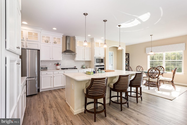 kitchen with light countertops, white cabinets, stainless steel appliances, and wall chimney exhaust hood