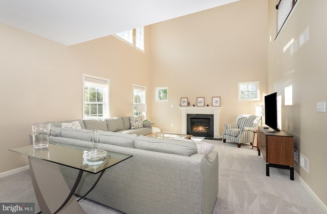 living area featuring baseboards, light carpet, a towering ceiling, and visible vents