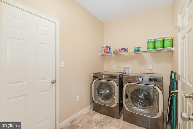clothes washing area featuring laundry area, washing machine and dryer, and baseboards