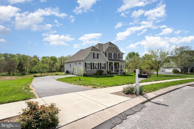 view of front of property featuring stone siding, driveway, and a front yard