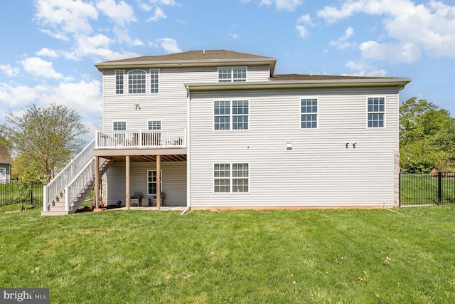 back of property featuring a lawn, fence, a wooden deck, and stairs