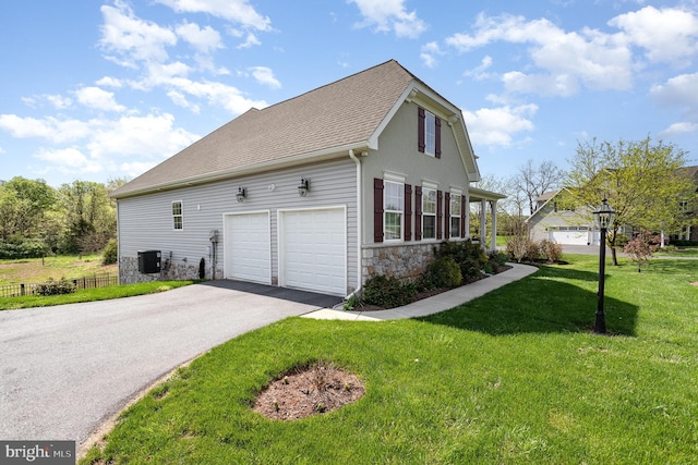 view of home's exterior featuring roof with shingles, stone siding, cooling unit, a yard, and driveway
