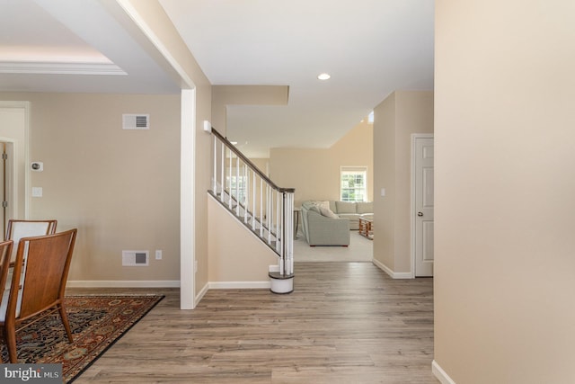 entryway with visible vents, baseboards, wood finished floors, and stairway