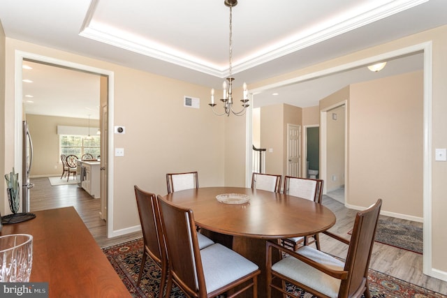 dining area featuring visible vents, baseboards, wood finished floors, and a chandelier