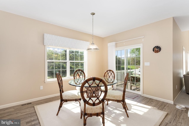 dining room featuring baseboards, visible vents, and light wood finished floors