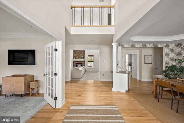 foyer with crown molding, baseboards, a stone fireplace, and wood finished floors