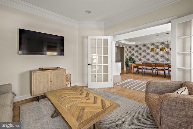 living area with french doors, crown molding, wood finished floors, baseboards, and wallpapered walls
