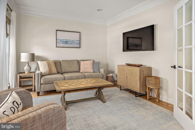 living room featuring baseboards, ornamental molding, and wood finished floors