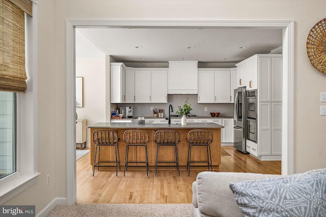 kitchen featuring white cabinetry, backsplash, and a kitchen bar