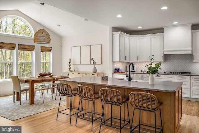 kitchen with a sink, backsplash, light wood-style flooring, and a wealth of natural light