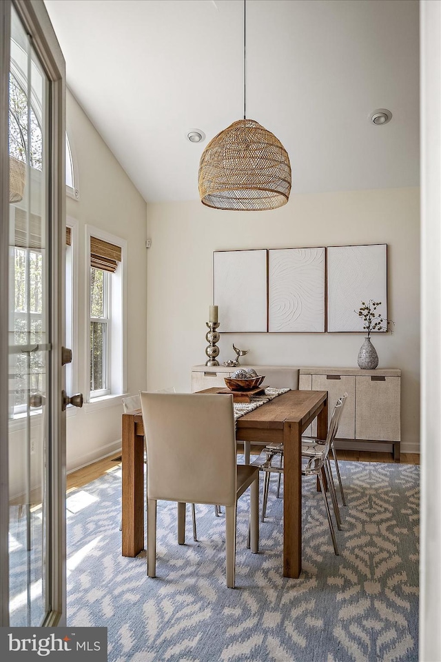 dining space with baseboards and vaulted ceiling