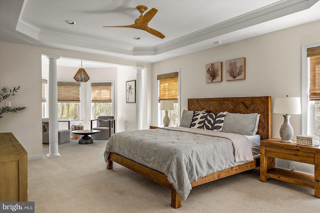 bedroom featuring crown molding, a raised ceiling, carpet, and decorative columns