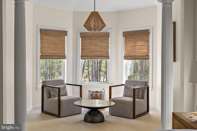 living area with baseboards, decorative columns, and carpet flooring