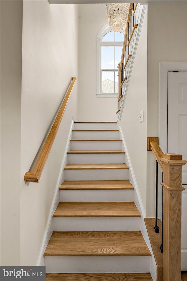 stairway with baseboards and a chandelier