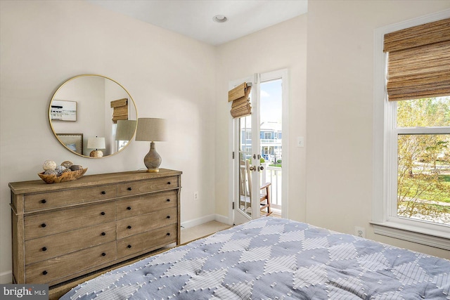 bedroom featuring baseboards, multiple windows, and light colored carpet