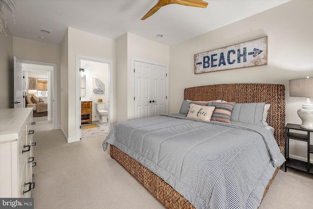 bedroom with a ceiling fan, light colored carpet, baseboards, a closet, and ensuite bath