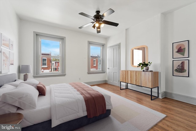 bedroom with baseboards, a ceiling fan, wood finished floors, and a closet