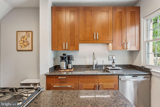 kitchen featuring a sink, dark stone counters, brown cabinetry, and stainless steel appliances