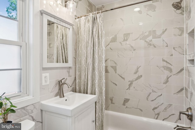 bathroom featuring vanity, shower / bath combo, and tile walls
