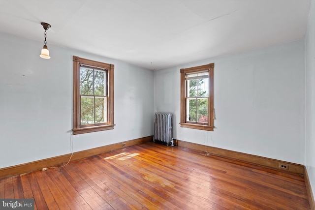 empty room with baseboards, radiator, and hardwood / wood-style floors