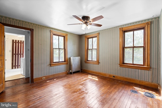 empty room with baseboards, radiator, and hardwood / wood-style floors