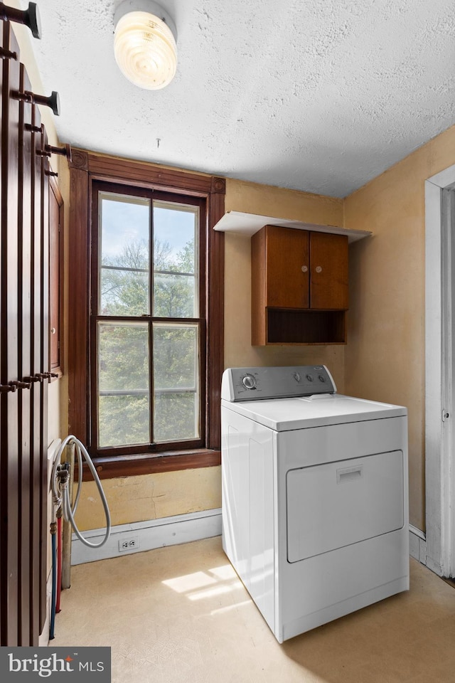 laundry room featuring baseboards, a textured ceiling, washer / dryer, and cabinet space