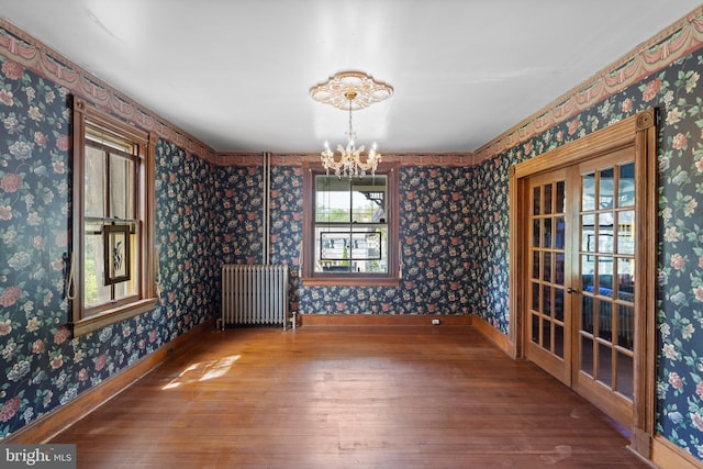 unfurnished dining area with hardwood / wood-style flooring, a notable chandelier, baseboards, and radiator
