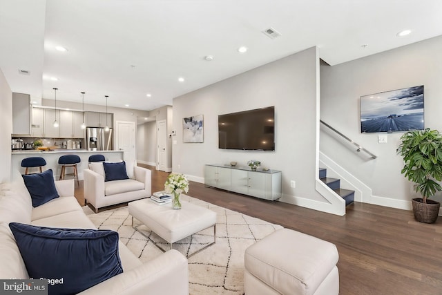 living area with recessed lighting, visible vents, light wood-type flooring, baseboards, and stairs
