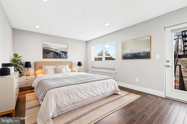 bedroom featuring baseboards, wood finished floors, visible vents, and multiple windows