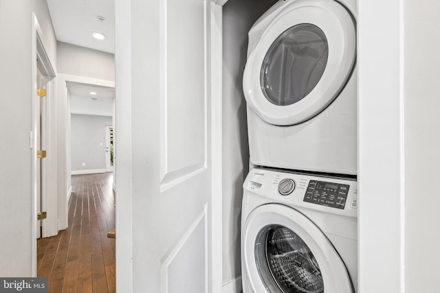 clothes washing area with recessed lighting, stacked washer / dryer, laundry area, wood finished floors, and baseboards