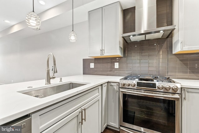 kitchen with a sink, gas range, pendant lighting, light countertops, and wall chimney exhaust hood