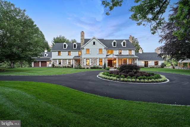 shingle-style home with a garage, a front yard, a chimney, board and batten siding, and driveway