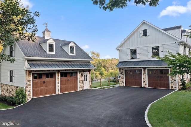 exterior space with a shingled roof, aphalt driveway, stone siding, board and batten siding, and a standing seam roof
